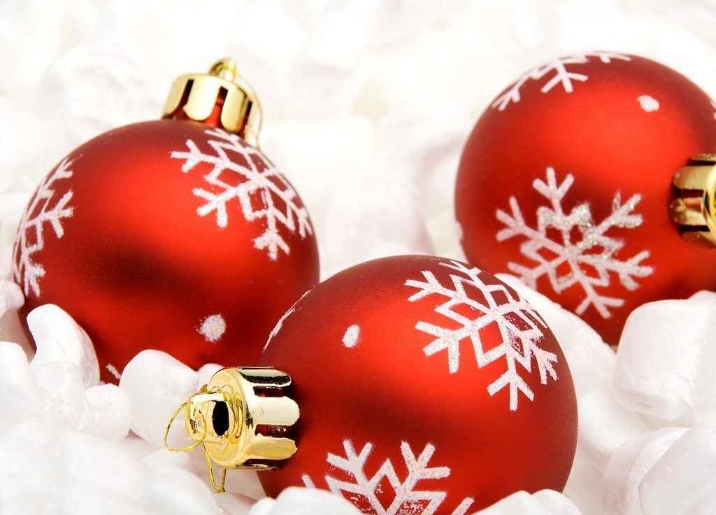 Vianočný obrázok s červenými ležiacimi bankami ozdobenými bielymi vločkami.