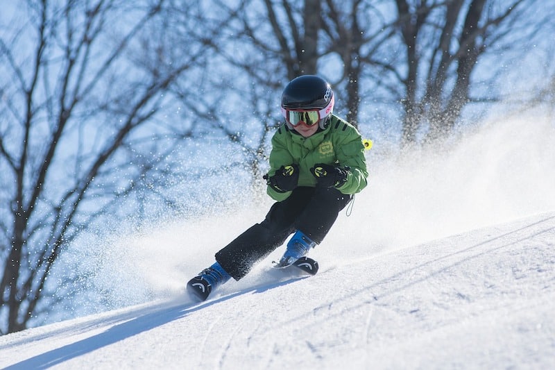 Chlapec divoko schádza svah na lyžiach.