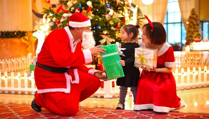 Vietnamský Santa Claus odovzdáva malému dieťaťu darček.
