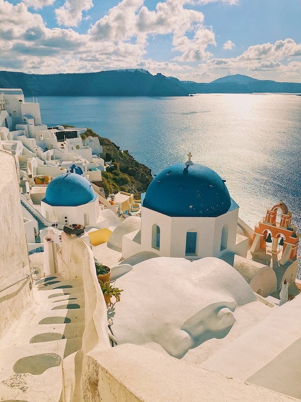 Grécke Santorini a jeho krásne modré strechy na bielych budovách, v diaľke slnkom osvietené more.