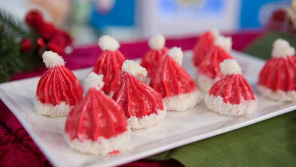 Vianočné pusinky v tvare čiapočiek Santa Clausa na tanieriku.