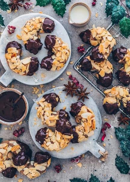 Vianočné rožky posypané plátkami mandlí a namáčané v čokoláde servírované na tanieroch.